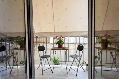 a balcony with three chairs and a table with flowers at Athenian Dream Apartment-Spacious Comfortable & Luxurious in a real Athenian neighborhood in Athens