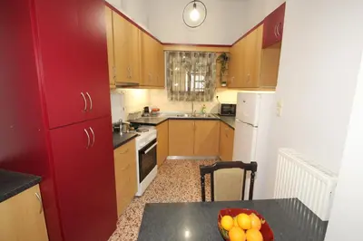 a kitchen with red cabinets and a table with a bowl of fruit at Bratis House Athens in Athens