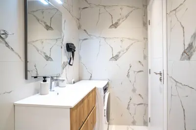 a bathroom with marble walls and a sink and a mirror at Heart Of Athens Apartments in Athens