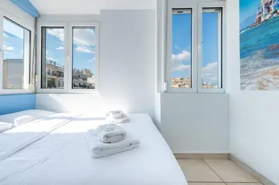 a white bedroom with windows and a bed with towels at Acropolis view Penthouse by WeHost Athens in Athens