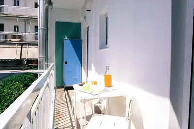a white table and chairs on a balcony with a blue door at ViLLaRa: Style, Hospitality & Design (City Center) in Athens