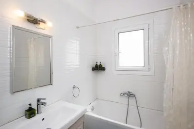 a white bathroom with a tub and a sink and a window at Spacious1 Bedroom Flat In The Heart Of Athens in Athens