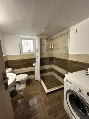 a bathroom with a shower and a toilet and a washing machine at Όμορφο διαμέρισμα (Αργυρούπολη) in Athens