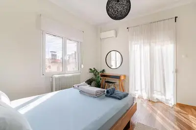 a white bedroom with a large bed and a window at AthenSunapartment top floor 5min metro in Athens