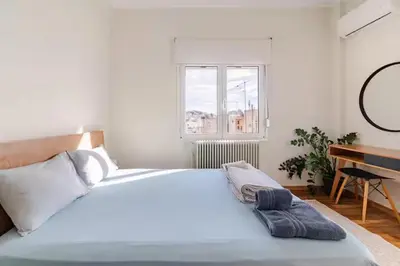 a bedroom with a large white bed and a desk at AthenSunapartment top floor 5min metro in Athens
