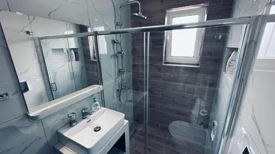 a bathroom with a shower and a sink and a mirror at Hodos Luxury APT near ATH-Airport in Markopoulo