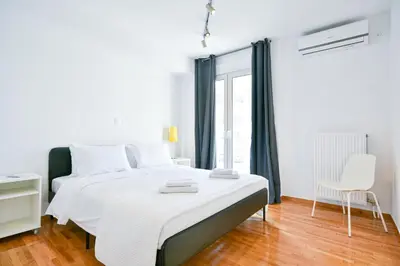a white bedroom with a bed and a chair at Delightful Penthouse in Athens