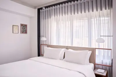 a bedroom with a bed with white sheets and a window at The Social Athens Hotel, a member of Radisson Individuals in Athens