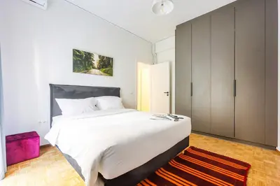 a bedroom with a large white bed and a purple rug at Stylish Apartment in Thissio l Dedicated Workspace in Athens