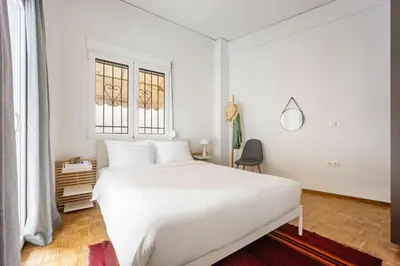 a white bedroom with a white bed and a window at Stylish Apartment in Thissio l Dedicated Workspace in Athens