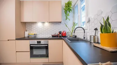 a kitchen with white cabinets and a black counter top at Stylish Apartment in Thissio l Dedicated Workspace in Athens