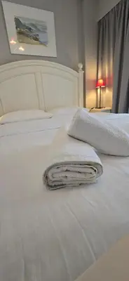a white bed with two towels on top of it at Luxury Vacation by LV in Athens