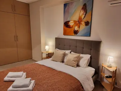 a bedroom with a large bed with a butterfly painting on the wall at Menelaou Cozy Apartment VIPGreece in Athens