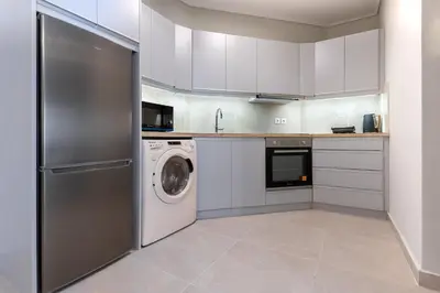 a kitchen with white cabinets and a washer and dryer at Phaedrus Living Luxury Flat Ampelokipoi in Athens