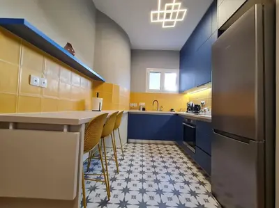 a kitchen with blue cabinets and a counter with stools at Simple & Noble in Athens