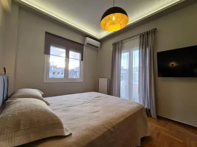 a bedroom with a large bed and two windows at Simple & Noble in Athens
