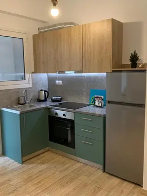 a kitchen with green cabinets and a refrigerator at Marina Alkamenous apartment in Athens