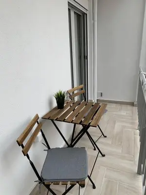 a wooden table and a chair in a room at Marina Alkamenous apartment in Athens