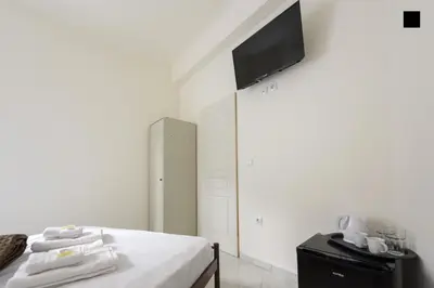 a bedroom with a bed with a tv on the wall at ATHENS COMMERCIAL in Athens