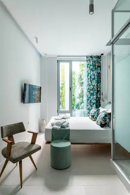 a bedroom with a bed and a chair and a window at Ciel Suites Athens in Athens