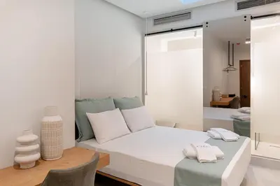 a bedroom with a large white bed with white pillows at Ciel Suites Athens in Athens