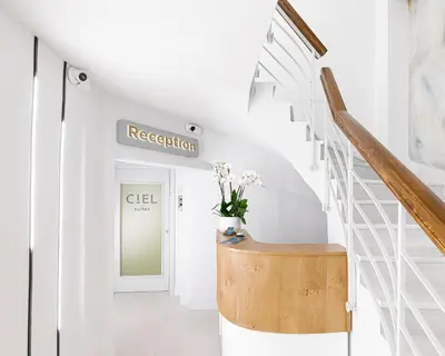 a white hallway with a staircase with a wooden stool at Ciel Suites Athens in Athens