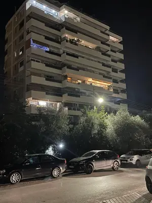 a parking lot with cars parked in front of a tall building at Endless Blue Studio in Glyfada in Athens