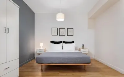 a bedroom with a bed with white walls and wooden floors at Deluxe Suite by Acropolis Cozy Suites in Athens