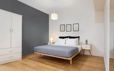 a bedroom with a bed with white walls and wooden floors at Deluxe Suite by Acropolis Cozy Suites in Athens