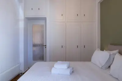 a white bed with two towels on top of it at Rare 1BR APT, next to the new Goulandris Museum in Athens