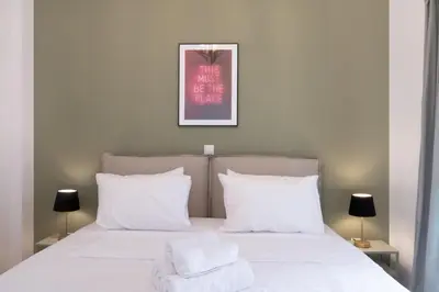a bedroom with a bed with white sheets and pillows at Rare 1BR APT, next to the new Goulandris Museum in Athens