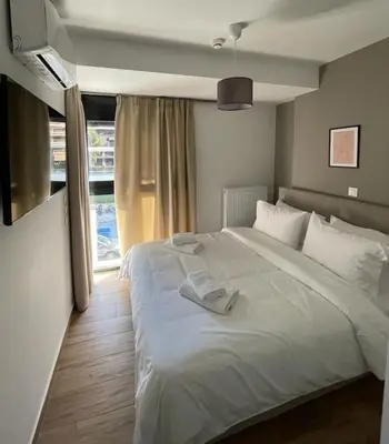 a bedroom with a large white bed and a window at Niarchos apartment III in Athens