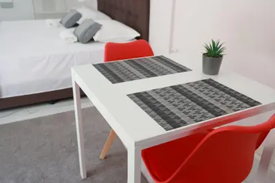 a white table with two red chairs and a bed at Lysandros Apartments in Athens, near the METRO in Athens