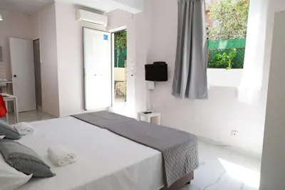 a white bedroom with a bed and a window at Lysandros Apartments in Athens, near the METRO in Athens