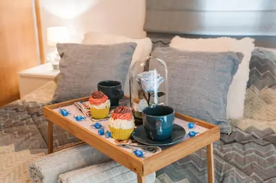 a tray with cupcakes and cups on a bed at Lovely seaside apartment next to Starbucks opposite the beach park of Flisvos in Athens