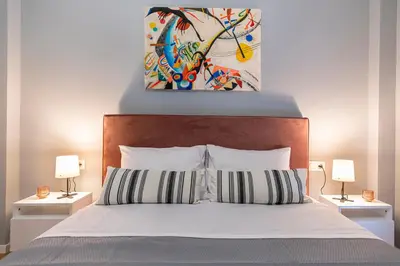 a bedroom with a bed with two lamps and a painting at Athenian center apartments in Athens