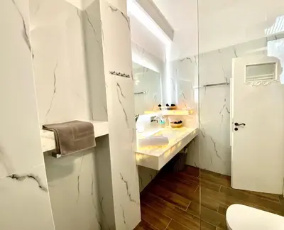 a white bathroom with a sink and a mirror at Athenian Condo in Athens