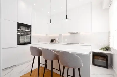 a white kitchen with two stools at a counter at Upscale Athens Luxury Penthouse in Athens