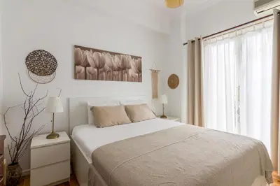 a white bedroom with a bed and a window at Cozy Apartment with Private Courtyard , Near Syngrou-Fix Metro Station in Athens