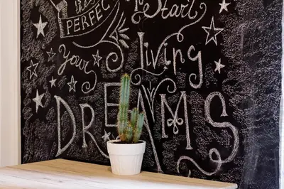 a chalkboard with a plant on a table with a wall with writing at Cozy Apartment with Private Courtyard , Near Syngrou-Fix Metro Station in Athens