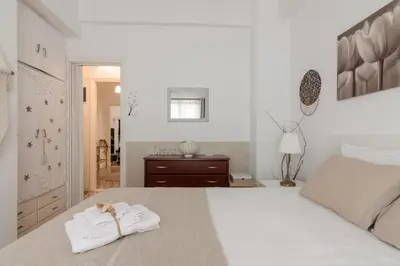 a white bedroom with a bed with towels on it at Cozy Apartment with Private Courtyard , Near Syngrou-Fix Metro Station in Athens