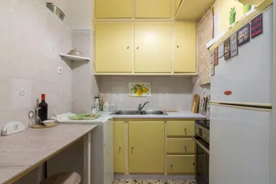 a kitchen with yellow cabinets and a white refrigerator at Cozy Apartment with Private Courtyard , Near Syngrou-Fix Metro Station in Athens