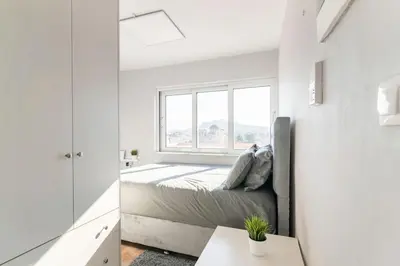 a white bedroom with a bed and a window at Acropolis from my bed in Athens