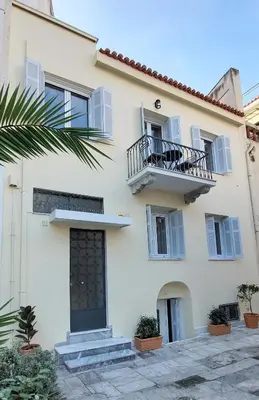 a white building with a balcony and a door at Athens Plaka Family Suites in Athens