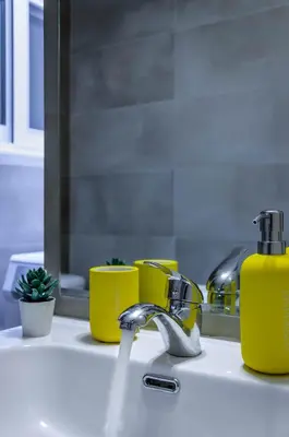 a sink with a faucet and yellow soap bottles at Renovated 2BD house close to Pireus port in Piraeus