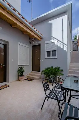 a patio with chairs and a table and a house at Renovated 2BD house close to Pireus port in Piraeus