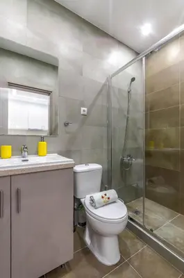 a bathroom with a toilet and a glass shower at Renovated 2BD house close to Pireus port in Piraeus