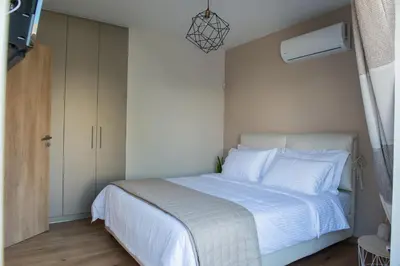 a bedroom with a bed with white sheets and a tv at Palmyra Athens in Athens