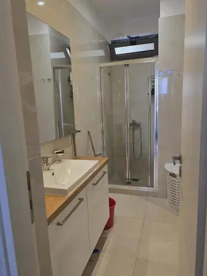 a white bathroom with a shower and a sink at A&A Apartment in Piraeus