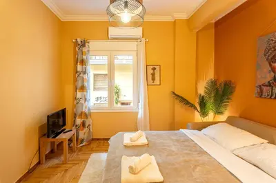 a bedroom with yellow walls and a bed and a window at Renovated 2 Bedroom Apartment in City Centre in Athens